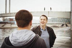 twee mannetje tiener- vrienden hebben een pret gesprek door de rivier- foto