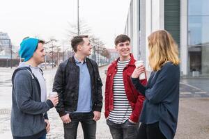 groep van jong volwassen vrienden hebben een gesprek terwijl staand samen Aan stad straat foto