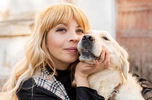 blonde vrouw die haar retrieverhond knuffelt foto