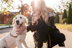 blonde vrouw die haar retrieverhond knuffelt in het zonlicht