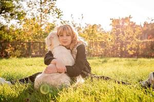 mooie blanke vrouw die haar gouden labrador retriever-hond knuffelt in een park in de zonsondergang foto