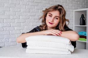 glimlachende jonge vrouw op een stapel handdoeken op witte bakstenen achtergrond foto