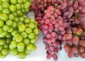 rood karmozijn met groen schijnen muscat pitloos druiven Aan wit schuim doos voor uitverkoop in fruit winkel Bij vlo markt foto