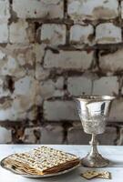 matzah en een zilver beker Aan een wit tafel, foto