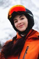 jong vrouw van Kaukasisch etniciteit looks naar de kant en glimlacht, verhogen haar hoofd naar de lucht, genieten van haar vakantie Bij de ski toevlucht foto