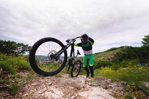 Mens duwt een berg fiets omhoog een berg. avontuur reizen door fiets. vrije stijl wedstrijd, berg beklimmen voor bergafwaarts foto