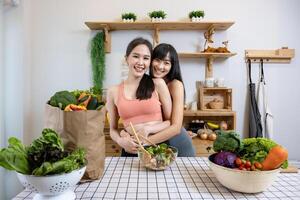 Aziatisch paar van dezelfde seks huwelijk knuffelen elk andere terwijl Koken gezond salade samen in keuken gedurende trots maand naar promoten gelijkheid en verschillen van homoseksueel en discriminatie foto