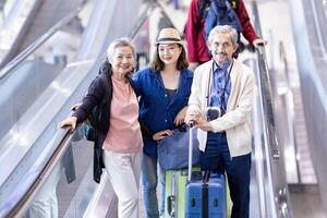 groep van Aziatisch familie toerist passagier met senior ouder gebruik makend van roltrap Bij de luchthaven terminal voor vliegmaatschappij reizen en vakantie vakantie concept foto