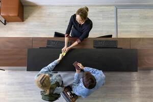 Kaukasisch toeristenpaar geeft paspoort aan de receptie bij de balie van de hotellobby om in te checken in de kamer voor internationaal reis- en vakantieconcept foto