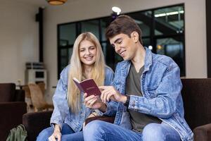 Kaukasisch reiziger paar is op zoek Bij Visa toestaan in de paspoort terwijl aan het wachten in vliegmaatschappij bedrijf vertrek lounge terminal aan het wachten voor instappen vliegtuig foto