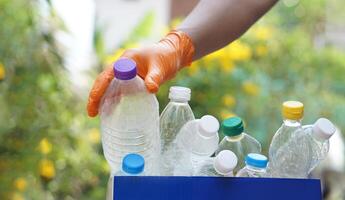 hand- houdt gebruikt plastic fles naar zetten in rommel bak voor recyclen. concept, sorteren vuilnis campagne voordat Gooi weg voor hergebruik of recyclen. milieu behoud. eco vriendelijk werkzaamheid. foto