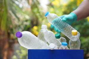 hand- houdt gebruikt plastic fles naar zetten in rommel bak voor recyclen. concept, sorteren vuilnis campagne voordat Gooi weg voor hergebruik of recyclen. milieu behoud. eco vriendelijk werkzaamheid. foto