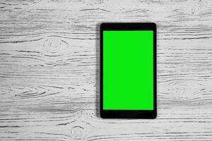 zwart tablet met groen scherm Aan een houten tafel bespotten omhoog. kopiëren ruimte chroma sleutel Scherm. foto