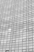 zwart en wit fragment van een modern kantoor gebouw. abstract meetkundig achtergrond. een deel van de facade van een wolkenkrabber met glas ramen. foto