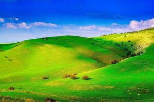 heuvels en bergen gedekt met jong groen gras en verlichte door de zon Aan een zonnig dag. foto