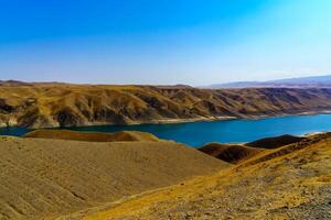 een uitgestorven een deel van de zaamin natuur reserveren in Oezbukistan Aan een zonnig zomer dag. visie van de bergen en reservoir. foto