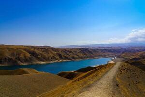 een uitgestorven een deel van de zaamin natuur reserveren in Oezbukistan Aan een zonnig zomer dag. visie van de bergen en reservoir. foto