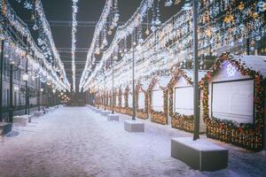 Kerstmis of nieuw jaar markt in een Europa met huizen versierd met speelgoed- ballen en slingers Bij nacht. wijnoogst film stijlvol. foto