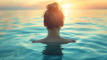 een vrouw drijvend in de oceaan gedurende zonsondergang foto