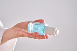 blauw serum met pipet in een dames handen in een gewaad. foto