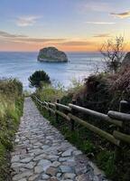 pad leidend naar de oceaan Bij san Juan de gaztelugatxe in Spanje gedurende zonsopkomst foto