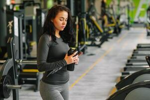 jong mooi vrouw drinken water in sport- Sportschool. foto