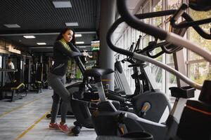 jong vrouw drinken water en nemen een breken na training in Sportschool foto