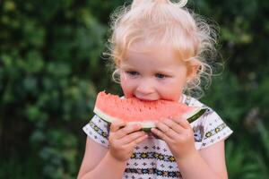 schoonheid weinig meisje eten watermeloen in park. foto
