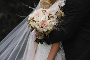 bruid staat in een wit bruiloft jurk met een boeket van bloemen foto