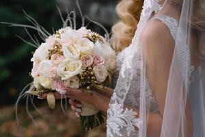 bruid staat in een wit bruiloft jurk met een boeket van bloemen foto