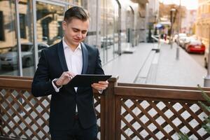 jong bedrijf Mens met tablet in de buurt van modern gebouw. foto