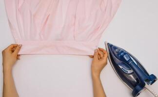 vrouw hand- strijken kleren top visie geïsoleerd Aan wit achtergrond. jong vrouw met ijzer strijken man's overhemd gezien van bovenstaand gedurende huiswerk. blauw ijzer Aan wit tafel foto