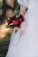 bruid staat in een wit bruiloft jurk met een boeket van bloemen. foto