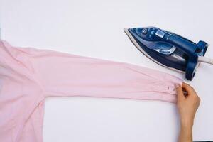 vrouw hand- strijken kleren top visie geïsoleerd Aan wit achtergrond. jong vrouw met ijzer strijken man's overhemd gezien van bovenstaand gedurende huiswerk. blauw ijzer Aan wit tafel foto