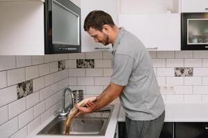 Mens snijdend vers vis in keuken in huis. Mens slachten vis voor koken. foto