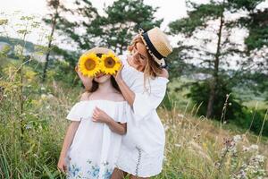 vrolijk moeder en haar weinig dochter hebben pret samen in de zomer achtergrond. gelukkig familie in de natuur achtergrond. schattig meisjes met kleurrijk bloemen foto