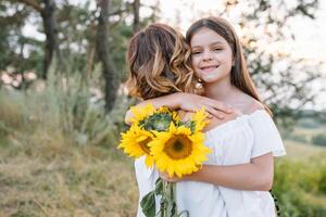 vrolijk moeder en haar weinig dochter hebben pret samen in de zomer achtergrond. gelukkig familie in de natuur achtergrond. schattig meisjes met kleurrijk bloemen foto