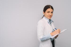 vrouw dokter in wit uniform is Holding kolven terwijl staand tegen wit achtergrond. foto