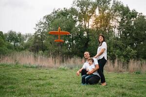 vader, moeder en zoon spelen met speelgoed- vliegtuig in de park. vriendelijk familie. mensen hebben pret buitenshuis. afbeelding gemaakt Aan de achtergrond van de park en blauw lucht. concept van een gelukkig familie. foto