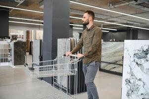 zelfverzekerd mannetje klant plukken uit muur tegel materialen voor badkamer in hardware op te slaan foto