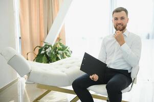 vriendelijk midden- oostelijk mannetje psycholoog glimlachen Bij camera gedurende behandeling sessie, werken in kliniek, vrij ruimte. gelukkig psychotherapeut poseren Bij kantoor. foto