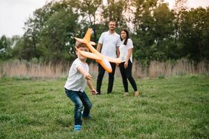 vader, moeder en zoon spelen met speelgoed- vliegtuig in de park. vriendelijk familie. mensen hebben pret buitenshuis. afbeelding gemaakt Aan de achtergrond van de park en blauw lucht. concept van een gelukkig familie foto