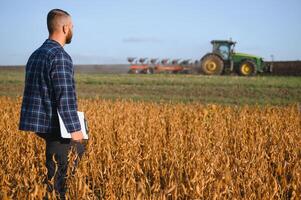 boer agronoom in soja veld- controle gewassen. biologisch voedsel productie en teelt foto