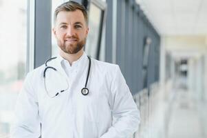 portret van knap jong dokter Aan ziekenhuis gang foto