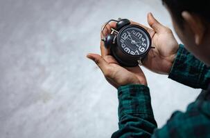 tijd beheer concept. Aziatisch Mens op zoek Bij zwart retro alarm klok. tijd naar wakker worden omhoog voor de ochtend- routine- foto