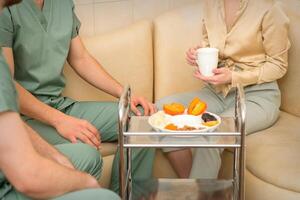 jong Kaukasisch vrouw overleg plegen met twee masseurs gedurende thee met droog fruit in de massage spa. foto