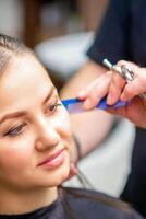 styling vrouw haar. mannetje kapper maakt kapsel voor een jong vrouw in een schoonheid salon. foto