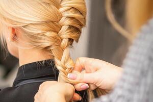 vlechten vlecht. handen van vrouw kapper vlechtjes lang vlecht voor een blond vrouw in een haar- salon. foto