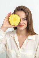 aantrekkelijk mooi mooi hoor jong Kaukasisch vrouw houden gesneden ananas aan het bedekken haar oog geïsoleerd Aan wit kleur achtergrond. foto