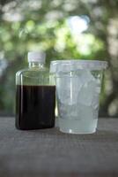 zwart koffie in plastic fles met plastic nemen weg kop met ijs kubussen. foto